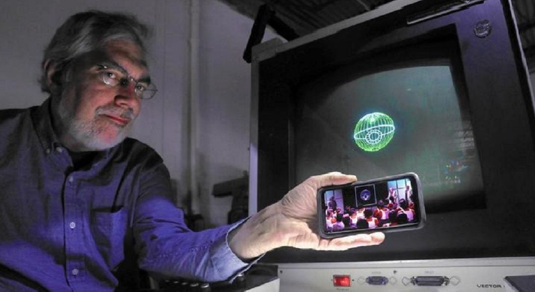 Aura Technologies President Steve Heminover holds a phone with a scene from the original “Star Wars” beside an image of the Death Star on the computer that was used to create digital effects for a small part of the 1977 film. Heminover was a student at the UIC lab where the effects were created. (Chris Sweda/Chicago Tribune)