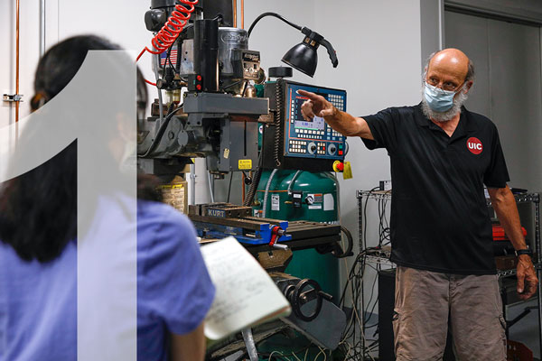 Two people wearing masks in a machine shop classroom