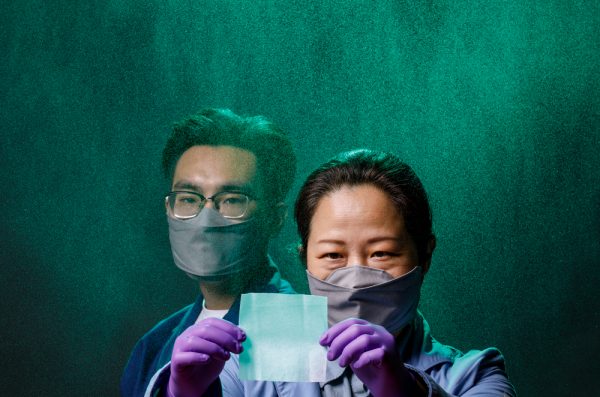 Two people wearing masks, one of them wearing gloves and holding up a filter